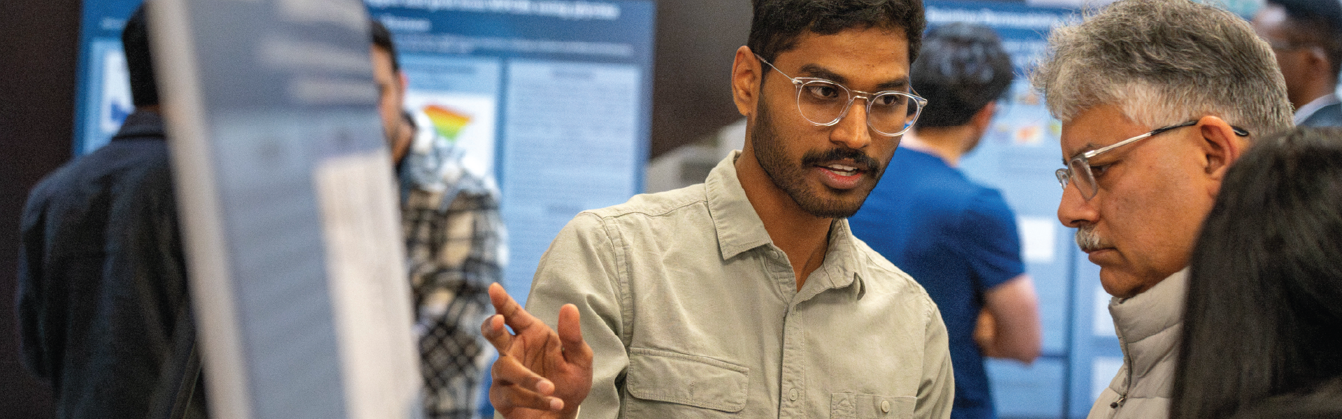 Graduate student presenting engineering research poster.