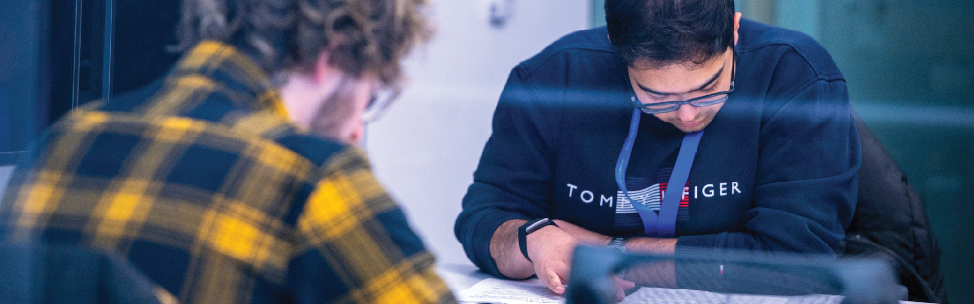 Two students sitting at table focused on paperwork.