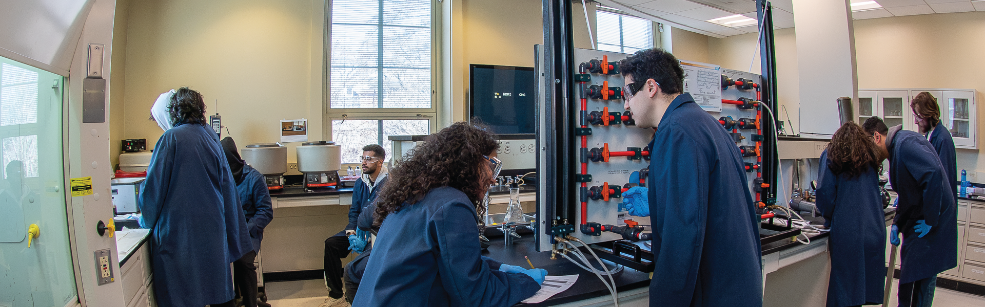 Students in blue lab coats in Baker Hughes Production Engineering Lab. 