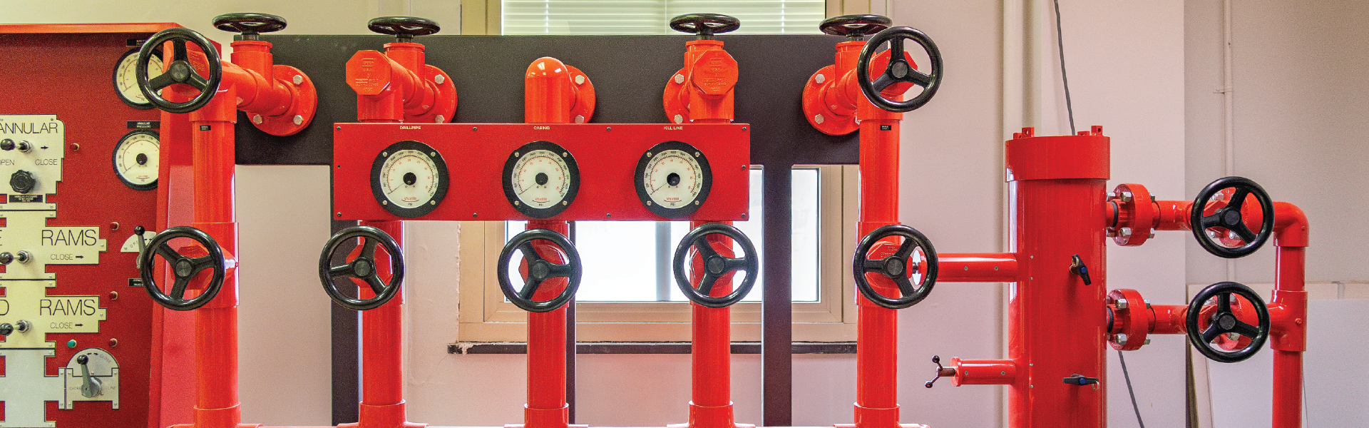 Red pipes and valves rig-floor simulator lab equipment.