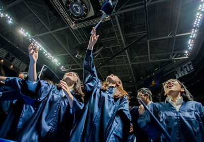 Penn State students tossing caps at graduation 