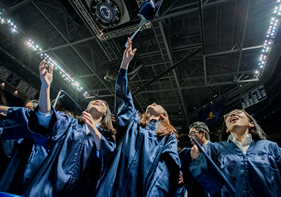 Penn State students tossing caps at graduation