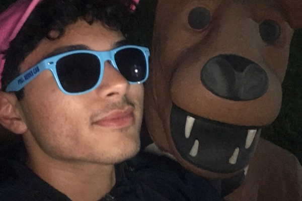 Student in sunglasses smiling with Nittany Lion