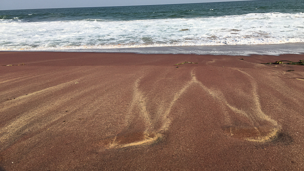 red beach with crashing waves