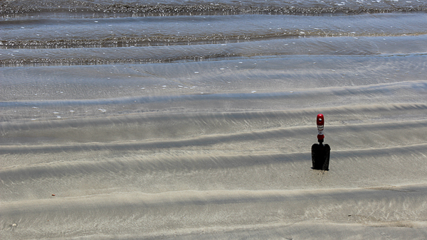 hand shovel standing in shallow water at beach