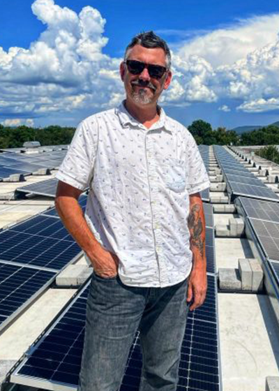 Peter Buck standing among solar panels. 