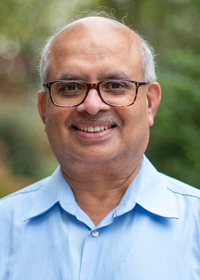 Sarma Pisupati outside smiling in front of greenery. 