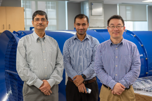 Sekhar Bhattacharyya, Ashish Kumar and Shimin Liu standing in front of a large blue fan in the mine ventilation lab.