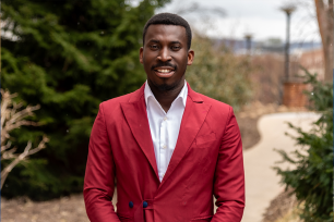 Patrick Sarpong in red suit jacket outside smiling. 