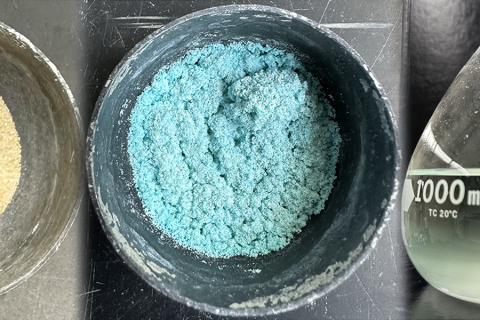 Light blue power in bowl beside glass container.