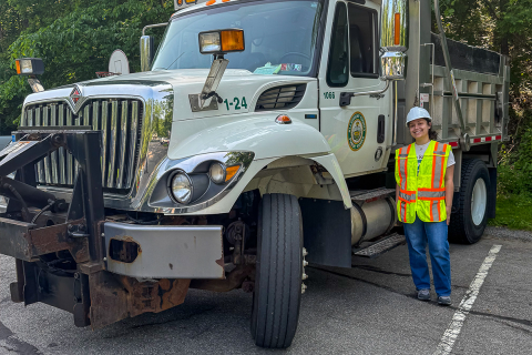 Veronica Sciulli standing beside a large dump truck. 