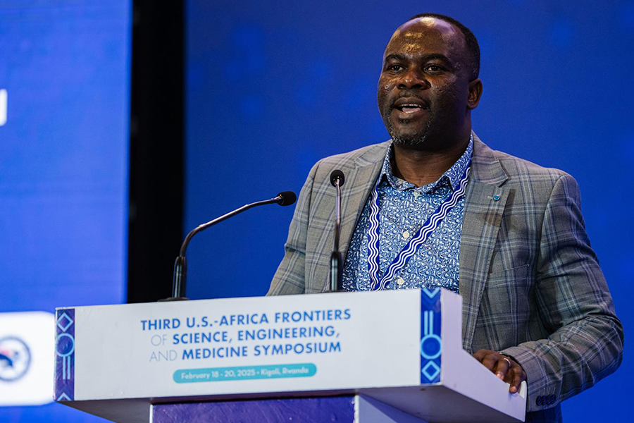 Nelson Dzade at podium in front of dark blue background. 