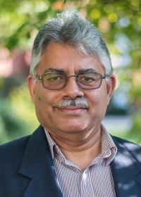 Sanjay Srinivasan outside in striped shirt and blue jacket. 